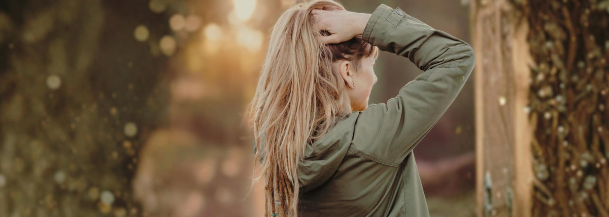 Person with dreadlocks massaging their scalp outdoors