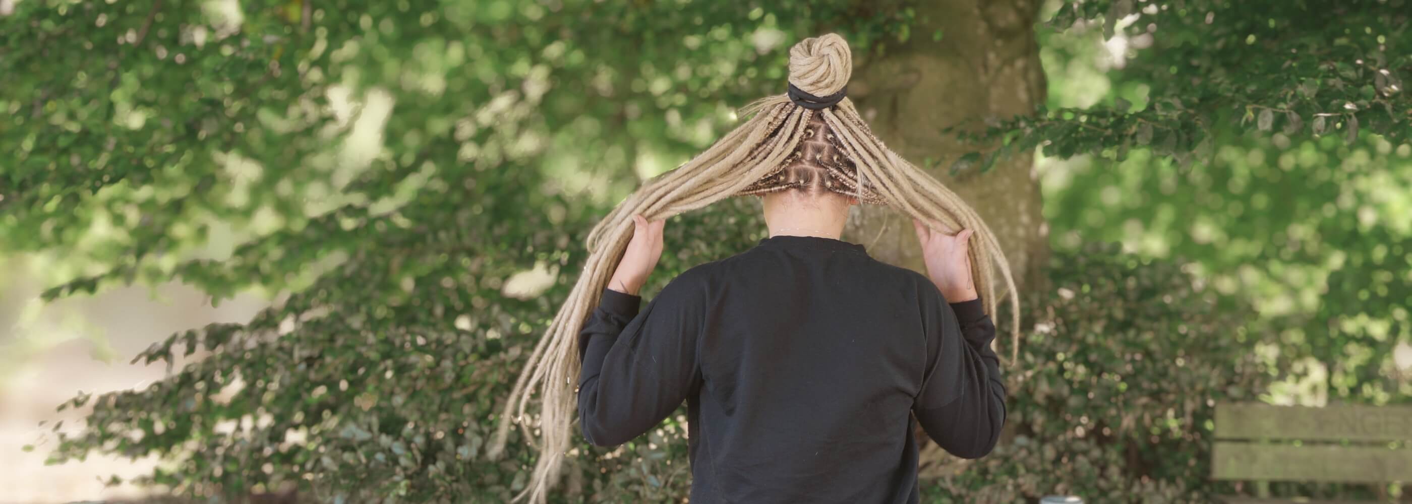 Person with newly created dreadlocks holding their new dreadlocks after a salon appointment, representing the beginning of a dreadlock journey.